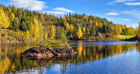 Panorama landscape of gold  colorful fall time by the lake Tokke in Telemark region. Blue sky with white clouds . Nice reflections of little stone island in lake water. Autumn in  Norway. 