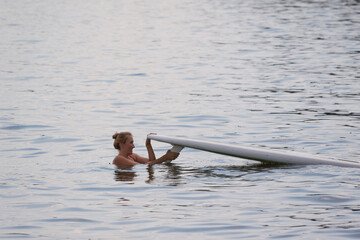 Young woman on the water with a surfboard