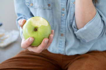 Close up of woman's hand holding a healthy and appetizing green apple