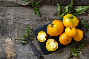 Fresh healthy raw ripe organic yellow tomatoes on a kitchen wooden table. The concept of Diet menu and harvesting. Top view flat lay background. Copy space.