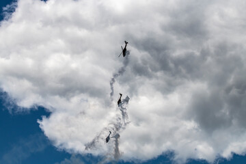 helicopters blow out a stream of smoke and make complex figures in flight against the background of the sky 