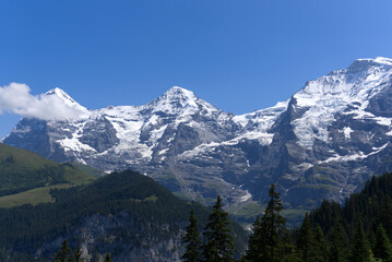 Mountain peaks Eiger, Mönch (Monk) and Jungfrau (Vrigin) at Bernese highland on a sunny summer day...