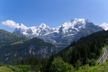Mountain peaks Eiger, Mönch (Monk) and Jungfrau (Vrigin) at Bernese highland on a sunny summer day with blue sky background. Photo taken July 20th, 2021, Lauterbrunnen, Switzerland.