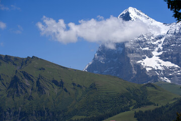 Fototapeta premium Mountain peak Eiger at Bernese highland on a sunny summer day with blue sky background and clouds in the foreground. Photo taken July 20th, 2021, Lauterbrunnen, Switzerland.