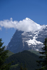 Mountain peak Eiger at Bernese highland on a sunny summer day with blue sky background and clouds...