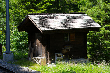 Wooden cabin at border of track of Lauterbrunnen–Mürren Mountain Railway on a beautiful summer day. Photo taken July 20th, 2021. Lauterbrunnen, Switzerland.