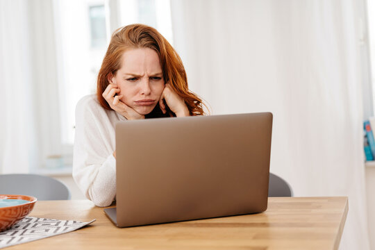 Frustrated or confused young woman frowning at her laptop