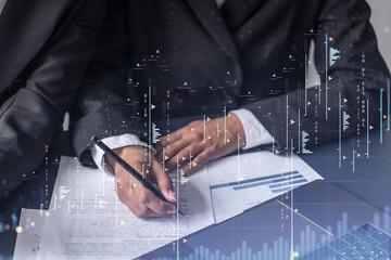 Two traders researching historic data to predict stock market behavior. Women in trading business concept. Forex and financial hologram chart over the table with the document.