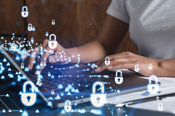 A woman programmer is typing a code on computer to protect a cyber security from hacker attacks and save clients confidential data. Padlock Hologram icons over the typing hands. Casual wear.