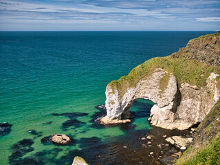 Natural arch and exposed rock strata near Portrush on the Antrim Causeway Coast Path - these rocks...