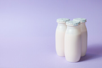 Bottles with probiotics and prebiotics dairy drink on light purple background.