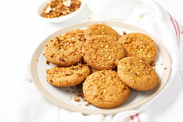 Healthy homemade oatmeal cookies with peanuts in a white plate on a light gray kitchen table closeup	