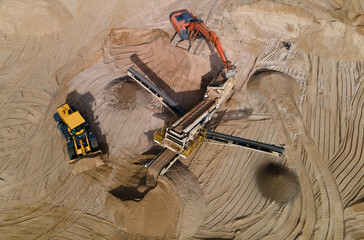 Arial view of the sand open-pit mining with heavy mining machinery. Mobile stone jaw crusher...