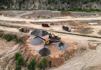 Arial view of the open pit mine. Front end loader loading gravel into stone jaw crusher in...