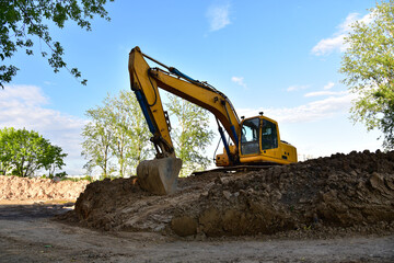 Fototapeta na wymiar Excavator on earthworks at construction site. Backhoe on earthmoving and foundation work. Heavy machinery and equipment. Earth-moving heavy equipment on road works