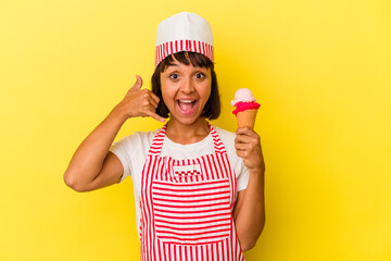 Young mixed race ice cream maker woman holding an ice cream isolated on yellow background showing a mobile phone call gesture with fingers.