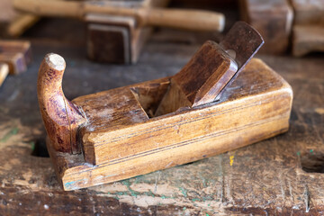 An old wooden plane on a workbench, shallow depth of field.