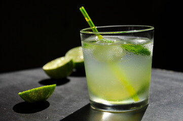 Natural juice with ice and lime on a black background.