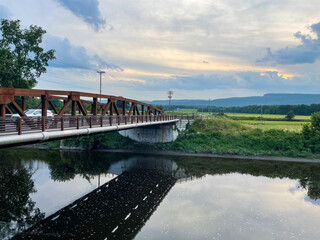 New Paltz, NY - USA - July 24, 2021: Horizontal sunset view of the Carmine Liberta Memorial Bridge, a two-lane steel through truss bridge over the Wallkill River. It carries New York State Route 299
