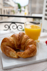 French breakfast, fresh baked croissant buttery pastry served with orange juice and old french houses on background