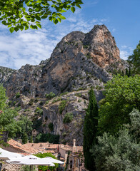 View on mountains cliff, old houses, green valley in remote medieval village Moustiers-Sainte-Marie in Provence, France