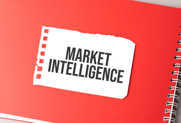 The word Market Intelligence on torn paper on red notepad,.
