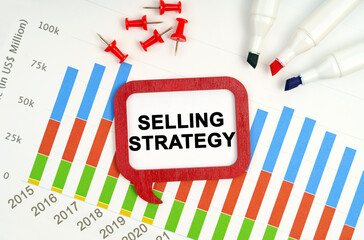 There are markers, charts and a sign on the table - SELLING STRATEGY