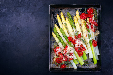Traditional backed white and green asparagus with tomatoes and parmesan served as top view on a...