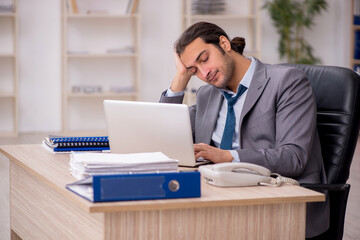 Obraz premium Young male employee unhappy with excessive work in the office