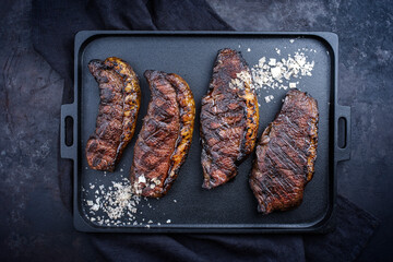 Modern style barbecue dry aged wagyu Brazilian picanha steaks from the sirloin cap of rump beef sliced and served as top view on a cast-iron design tray with copy space