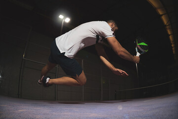 a young paddle player jumping on the plank to hit the ball.