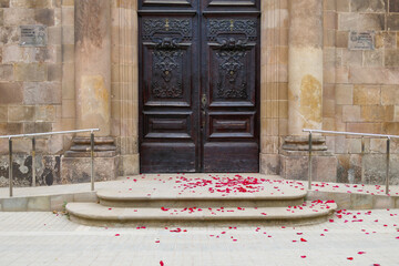 Red rose flower petals on the floor in front of the door of a church after a wedding. Divorce,...