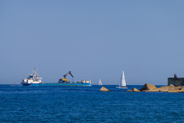 Excavator working industrial machine moved by a ship on the sea water. Nautical engineering floatingequipment