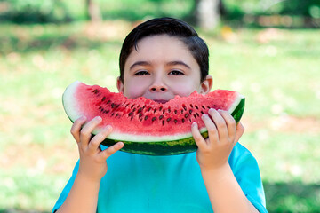 child holds watermelon, healthy portrait with nature in the background and sunlight