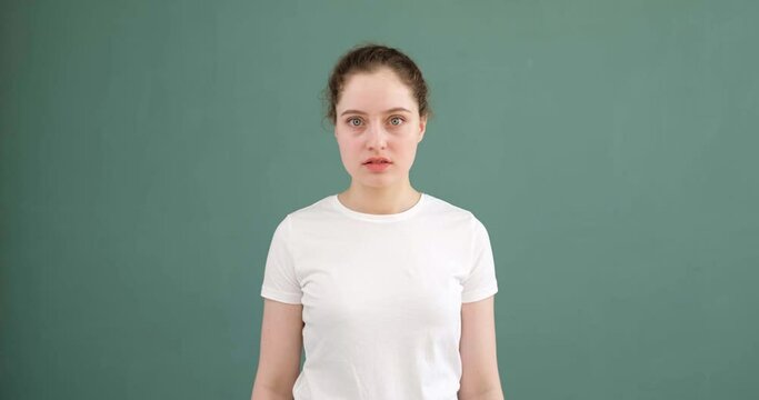 A young girl says no and gestures with her fists. Colored background, white t-shirt.