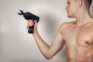 Fototapeta na wymiar Sportsman holds sports gun shock massage in medical office of gym