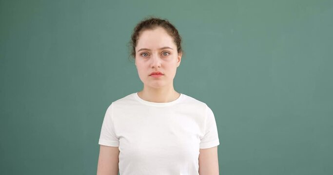 A young girl says come on and gestures. Colored background, white t-shirt.