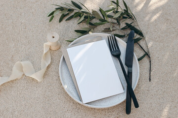 Festive wedding summer table setting. Black cutlery, olive branch, silk ribbon on dotted white...