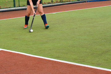 female hockey player running and passing the ball in a field