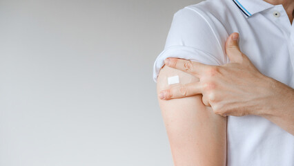 Unrecognized Vaccinated Man Showing Arm With Medical Patch Plaster After Covid-19 Vaccine Injection. Coronavirus Vaccination Advertisement Campaign. Vaccine Sign Done