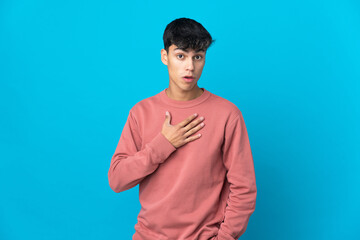 Young man over isolated blue background surprised and shocked while looking right