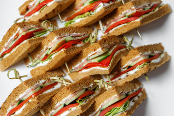 A plate of sandwiches with a crispy toasted crust on wooden skewers.