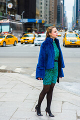 Dressing in a blue faux fur coat,  patterned dress, black leggings and leather shoes, a pretty...