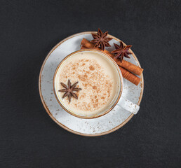 Masala chai tea on a dark background closeup. Traditional Indian hot drink with milk and spices....