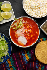 Mexican food. Red pozole with chicken on dark background