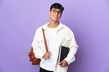 Young student man over isolated purple background posing with arms at hip and smiling