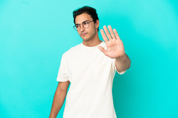 Caucasian handsome man over isolated blue background making stop gesture and disappointed