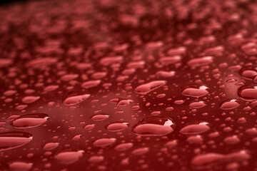 Water droplets on shiny red metallic surface with limited depth of focus