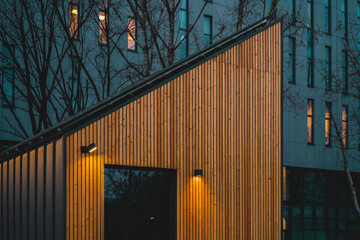 Triangular House with wooden facade with light illumination. Modern. Illuminated. Texture. Door....