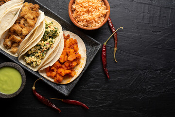 Different types of tacos also called guisados on a dark background. Mexican food